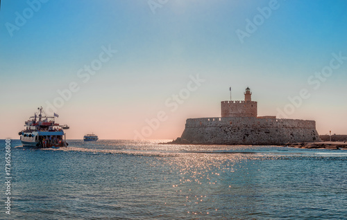 The cruising boats leave Mandraki harbor and the Fort of Saint Nicholas that guards the harbour. Mandraki is the main harbour of Rhodes, in Rhodes Island, Dodecanese, Greece