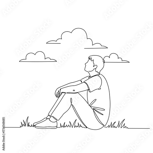 Young man sitting on grass and looking at clouds in the sky  