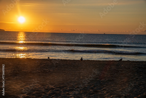 Stunning sunset over the calm sea, with warm golden and orange hues reflecting on the water. The peaceful coastal scene evokes relaxation, romance, and natural beauty, perfect for themes of travel,
