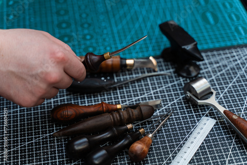 Fotomural Traditional wooden-handled awls and cutters beside a small anvil illustrate timeless craftsmanship and dedication to bespoke design