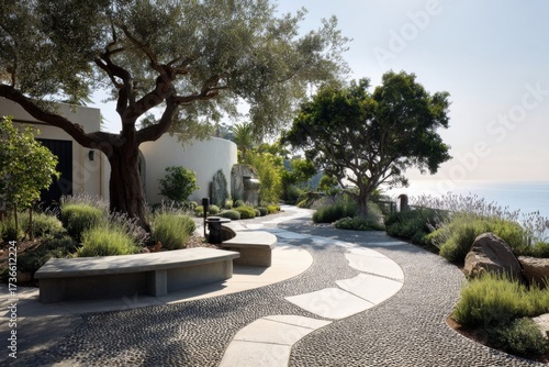 A serene pathway winds its way through a peaceful garden by the sea, adorned with distinctive stone designs and surrounded by vibrant greenery. It basks under the bright, clear sky at midday.