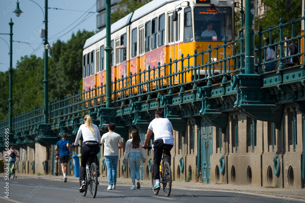 Obraz premium People biking and walking against old tram on overpass