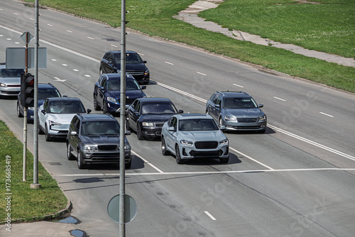 Many cars stopped at an intersection at a red traffic light. Front view of cars on the road
