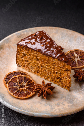 A slice of sweet layered cake covered in chocolate with nuts and caramel. A slice of chocolate cake