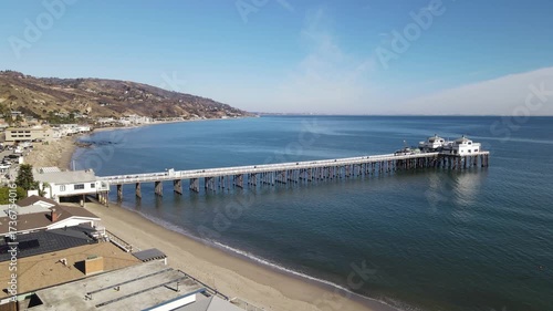 Aerial drone view of Malibu pier with a long sandy beach and the Pacific ocean. 