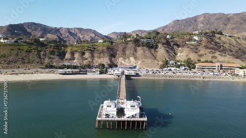 Aerial drone view of Malibu pier with a long sandy beach and the Pacific ocean.  