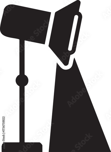 A black silhouette of a studio spotlight emitting a beam of light isolated on white background