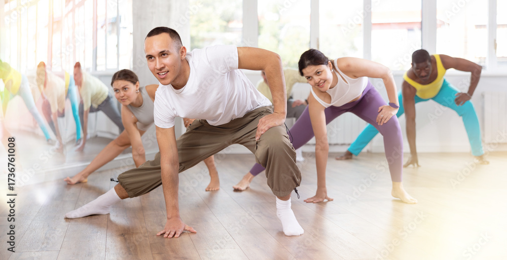 Obraz premium Group of multicultural men and women doing warm-ups before dance class in studio