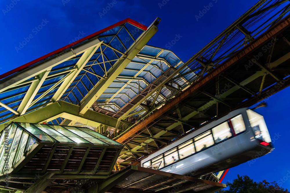 Fototapeta premium Nachtaufnahme der Wuppertaler Schwebebahn an der Haltestelle Kluse, Wuppertal, Deutschland