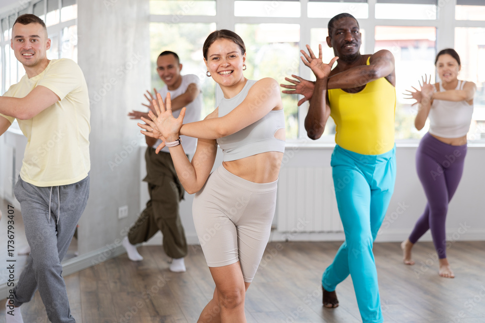 Naklejka premium Positive young girl engaged in active dance together with other attendees of dancing courses