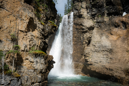 Waterfall cascading powerfully in a rocky gorge with turquoise water below