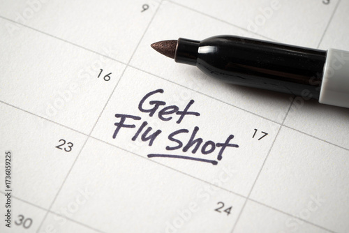 Φωτογραφία A close-up of a calendar with a handwritten note saying Get Flu Shot, serving as a reminder for an important health appointment