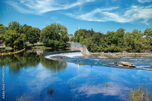 Waterfall with small hydro electric generation, daytime, blue skies and clouds, church in distance, nobody