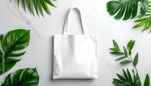 White Tote Bag Mockup on Marble Surrounded by Green Tropical Leaves