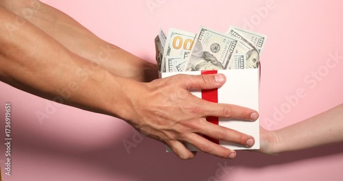 Woman gifting man money on pink background, closeup