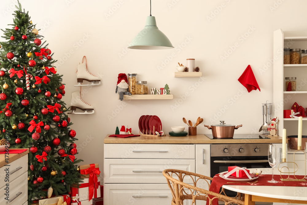 Obraz premium Interior of light kitchen with Christmas tree, counter and shelves