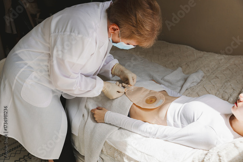 An adult nurse changes a patient's colostomy bag.