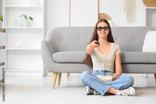Young woman in 3D glasses with remote controller and popcorn watching TV at home Free Download Young woman in 3D glasses with remote controller and popcorn watching TV at home - GFXLoad