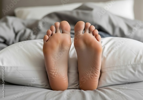 Restful slumber concept featuring bare feet resting on a soft pillow