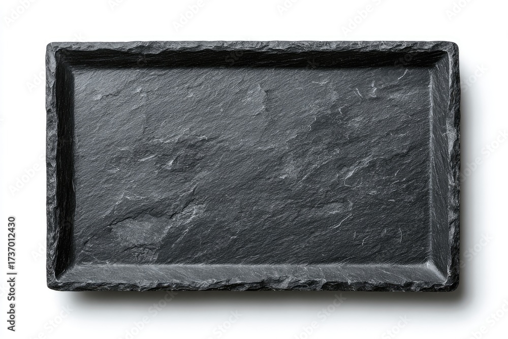 Fototapeta premium Overhead shot of a rectangular, textured, greyish-black stone serving tray with rough edges, shadow