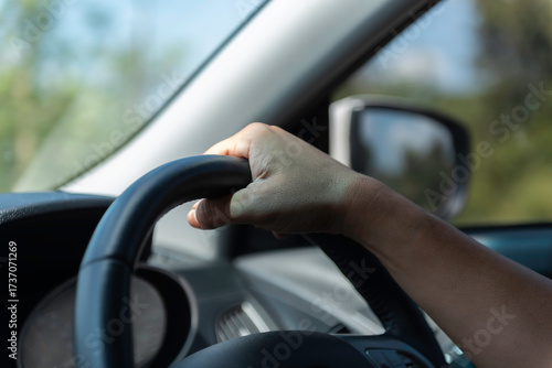 Male hands on steering wheel while driving on the road. Interior car view, concept of travel, freedom, driving safety, transportation, road trip, and automotive lifestyle.
