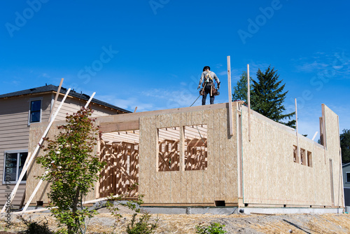 Canvas-taulu New housing development construction project, carpenter on wall in safety harnes
