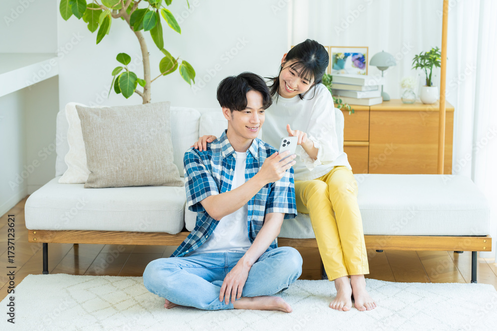 Fototapeta premium リビングでスマホを見るカップル
