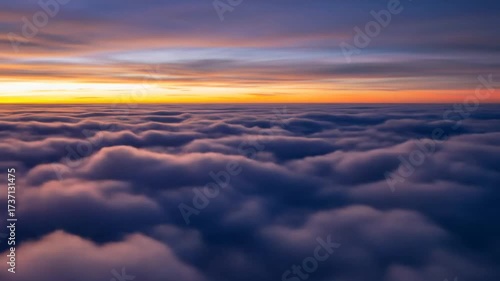 Aerial view of fluffy clouds illuminated by a vibrant orange and purple sunset