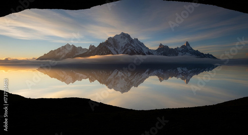 Mont blanc mountain range reflecting in still water under a cloudy sky creating a dramatic and scenic alpine landscape view