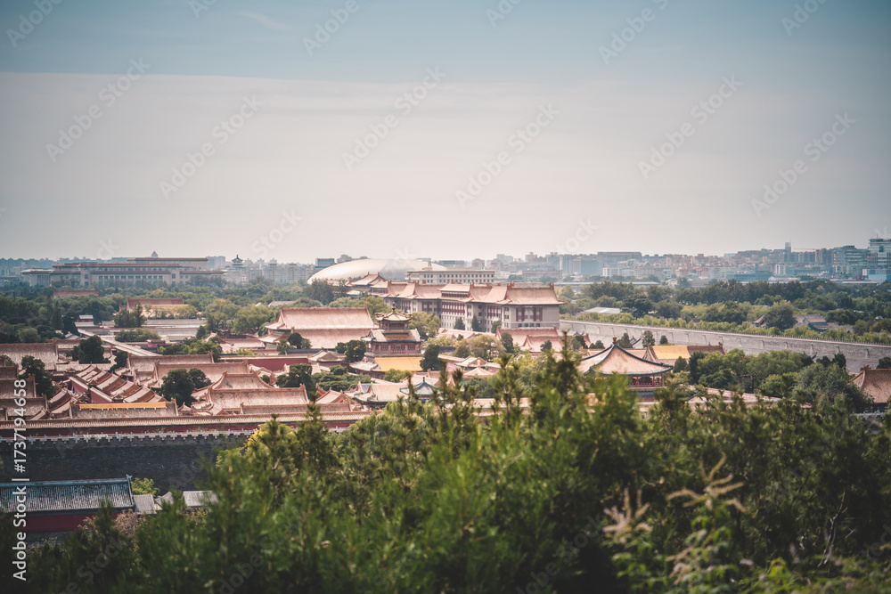 Fototapeta premium A daytime vista offers a scenic view of the Palace Museum in Beijing, showcasing ancient architecture amidst lush greenery under a cloudy sky. Capturing the essence of traditional Chinese heritage and