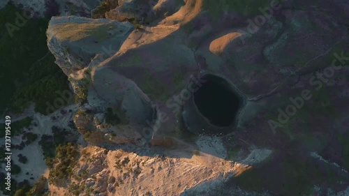 Drone video of the alpine lake Drakolimni Tymfis surrounded by mountain peaks at sunrise. Stunning natural scenery perfect for travel, adventure, and documentary projects.