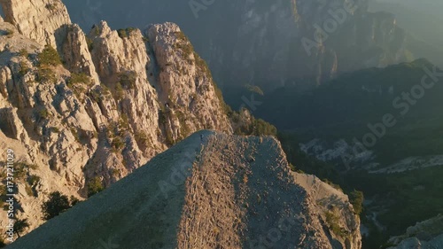 Aerial sunrise footage of mountain peaks with dramatic shadows and glowing ridges. Serene landscape perfect for documentaries, travel films, and adventure content.