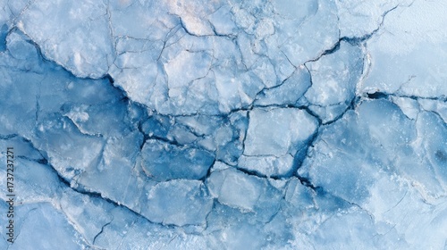 Abstract aerial view of icy surface with fissures and a gradient of light blues