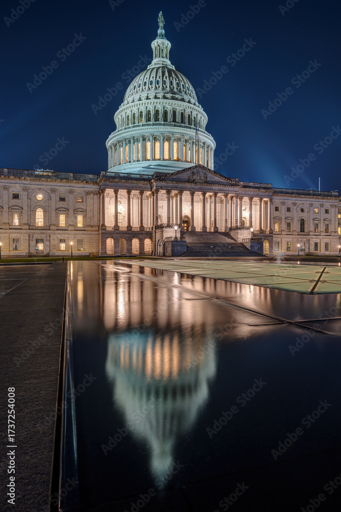 Fototapeta premium The illuminated U.S. Capitol Building in Washington D.C. at night with a reflection in a small puddle