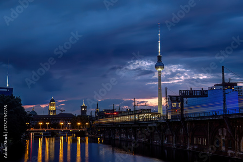The famous Television Tower and the river Spree with a motion blurred train in Berlin at night