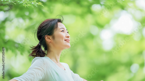 Woman enjoying fresh air in green forest with positive energy and relaxation
