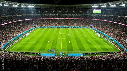 Illuminated Football Stadium at Night - A large, packed football stadium at night, brightly lit, showcasing a soccer game in progress.