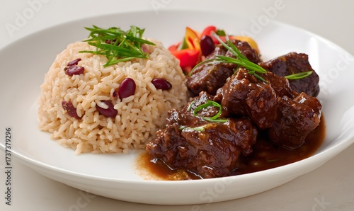 Caribbean food, featuring rich brown stewed oxtail with butter beans in a glossy sauce, served alongside a a mound of light brown Jamaican rice mixed with red kidney beans