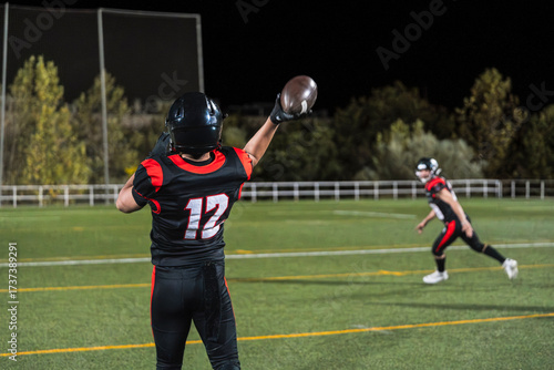 Bilde på lerret American football quarterback passing ball during a night game on a floodlit tur