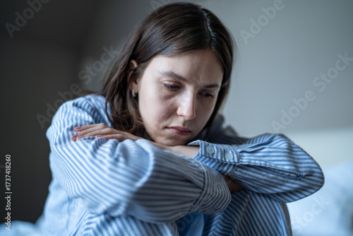 Exhausted depressed woman sits in pajamas feels unmotivated, frustrated to life lost in negative thoughts. Sad female overwhelmed by mental disorder suffering from loneliness, lack of self-confidence