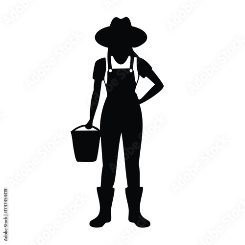 Silhouette of a woman farmer holding a bucket overalls