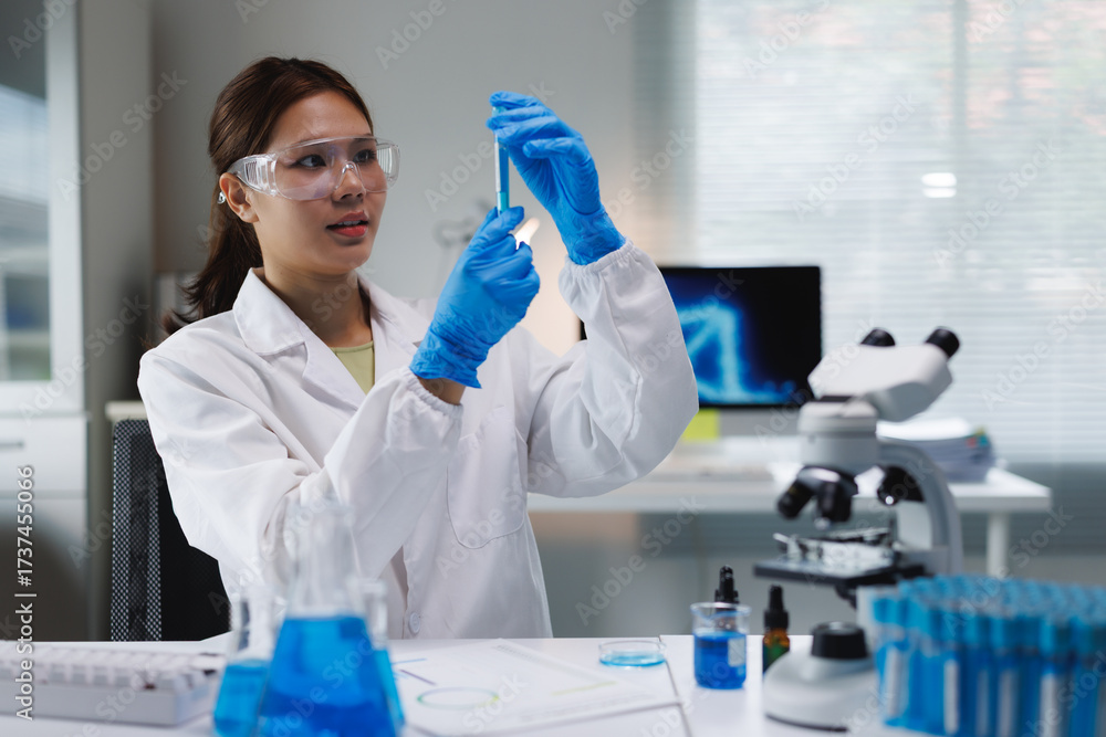 Fototapeta premium Young woman scientist examining test tube in laboratory