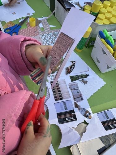 A girl cuts paper with scissors at a collage workshop