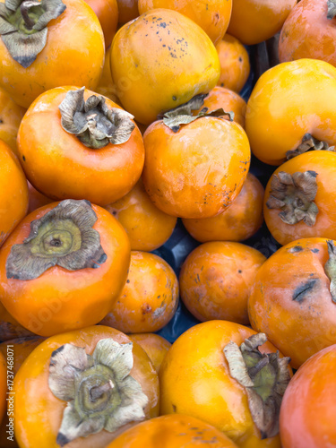 Fresh ripe persimmons at market stall, orange seasonal autumn fruit background