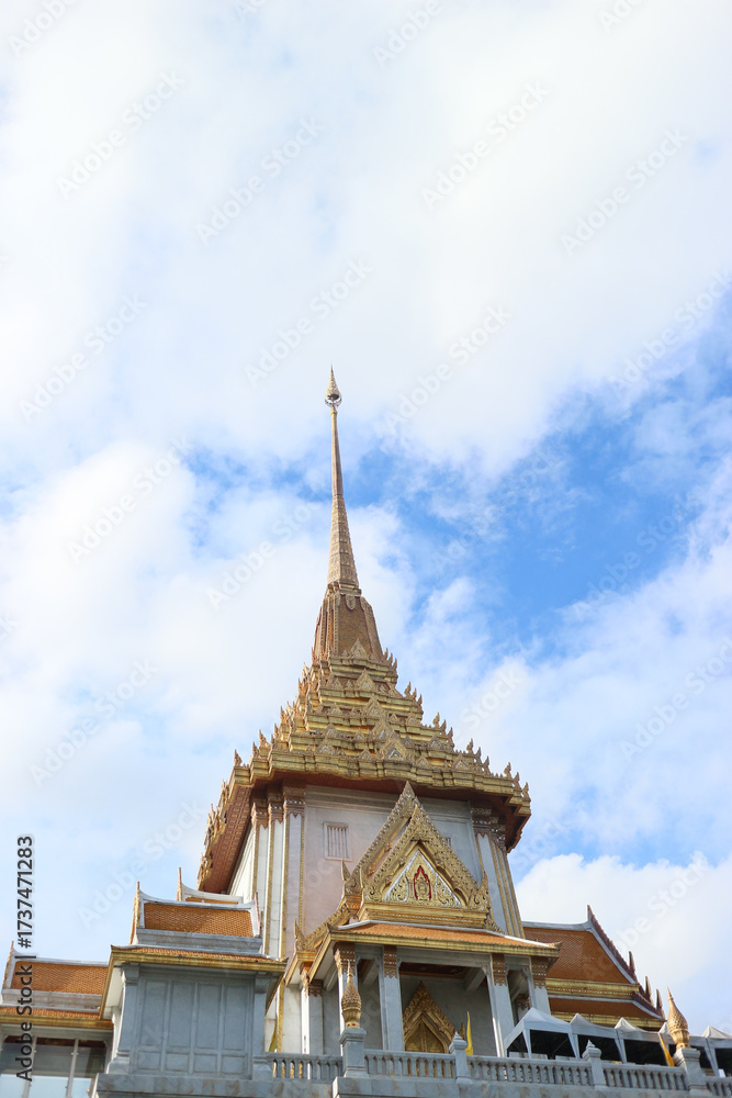 Fototapeta premium Golden stupa of Wat Traimit in Bangkok’s Chinatown, rising against a bright blue sky. A famous Thai temple known for the Golden Buddha and stunning architecture.