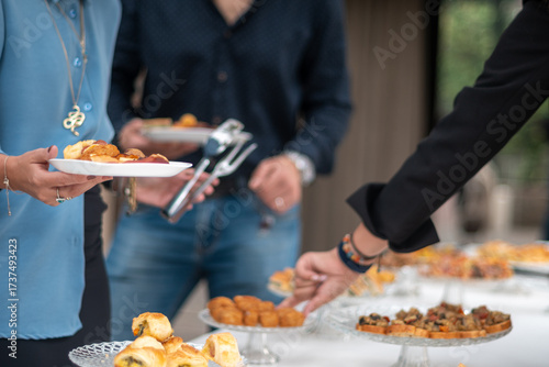 People gathering around a buffet table selecting small appetizers and finger foods during an informal social event celebration