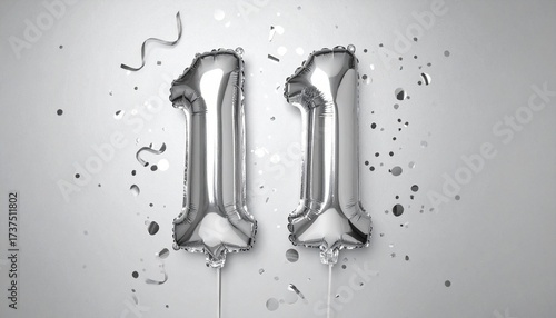 Silver balloon number 11 with confetti on solid colored background. Photo for anniversary or birthday party