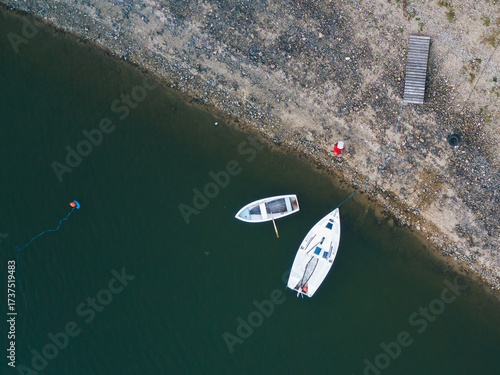Top-Down Aerial View of Sailboat and Rowboat on Dark Green Lake Water.