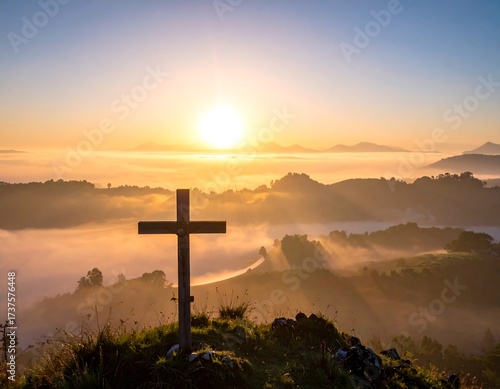 Sunrise over misty mountains with wooden cross