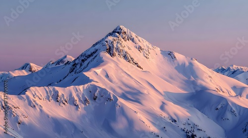 Majestic snow-covered mountain range dominates the frame, its rugged peaks illuminated by soft, golden sunlight during a beautiful sunset, creating a sense of tranquility and wilderness against a...